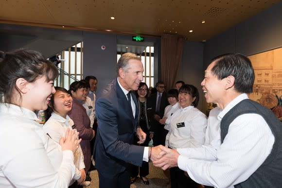 Starbucks Executive Chairman Howard Schultz, center, shakes the hand of an employee in a Chinese Starbucks.