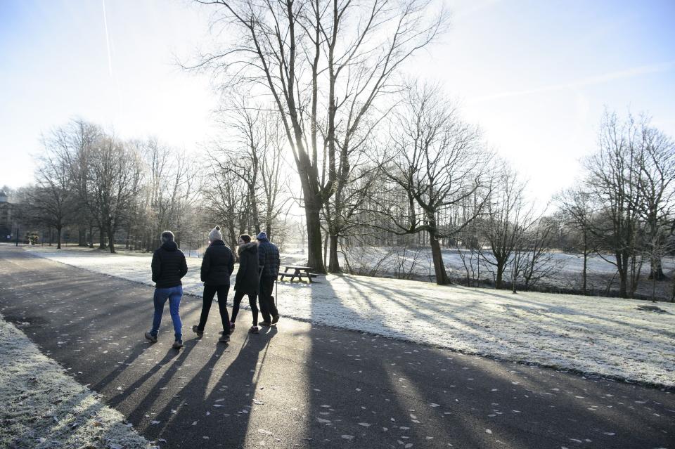 People stroll in widespread frost in Glasgow's Pollok Park, as temperatures plummet across the UK.