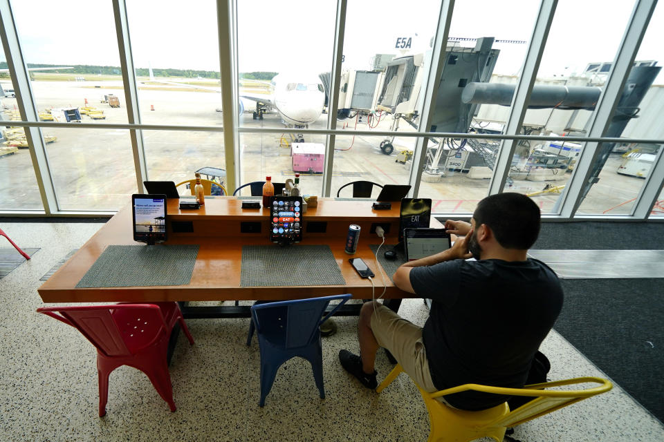 A traveler uses a tablet to choose seats on a plane at George Bush Intercontinental Airport, Friday, July 1, 2022, in Houston. The July Fourth holiday weekend is off to a booming start with airport crowds crushing the numbers seen in 2019, before the pandemic. (AP Photo/Julio Cortez)