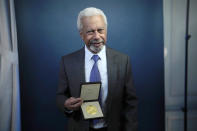 Abdulrazak Gurnah, a Tanzanian-born novelist and emeritus professor who lives in the UK, poses for photographs with his 2021 Nobel Prize for Literature medal after being presented it by the Ambassador of Sweden Mikaela Kumlin Granit in a ceremony at the Swedish Ambassador's Residence in London, Monday, Dec. 6, 2021. The 2021 Nobel Prize ceremonies are being reined in and scaled-down for the second year in a row due to the coronavirus pandemic, with the laureates receiving their Nobel Prize medals and diplomas in their home countries. (AP Photo/Matt Dunham)