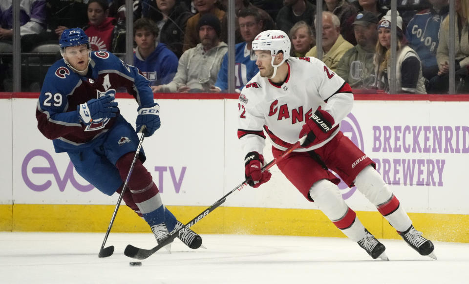 Carolina Hurricanes defenseman Brett Pesce, right, collects the puck as Colorado Avalanche center Nathan MacKinnon defends during the first period of an NHL hockey game Saturday, Nov. 12, 2022, in Denver. (AP Photo/David Zalubowski)