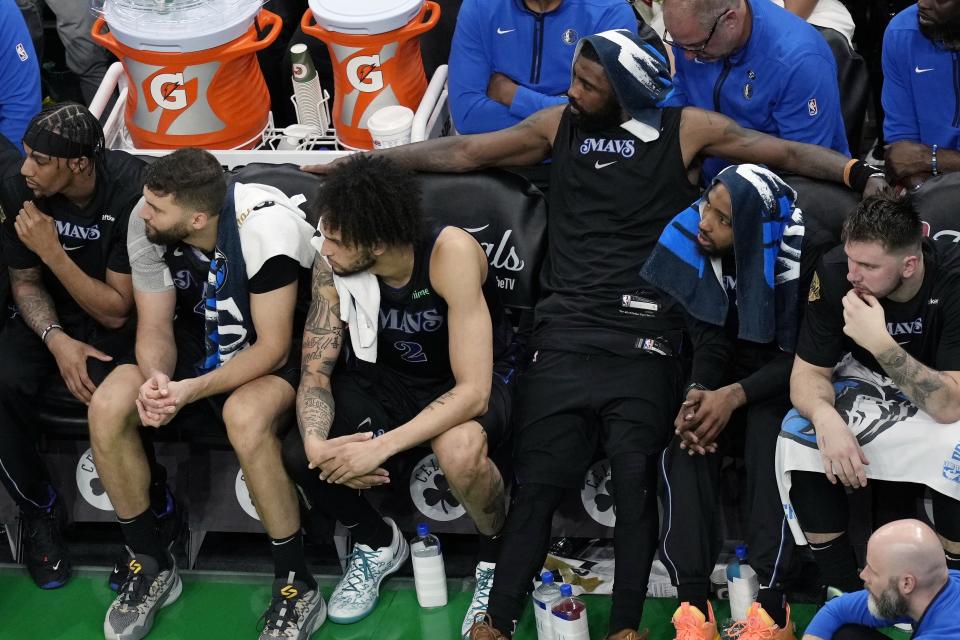 Dallas Mavericks' Kyrie Irving, third from right, watches from the bench with teammates late in the second half of Game 1 of the basketball team's NBA Finals against the Boston Celtics on Thursday, June 6, 2024, in Boston. (AP Photo/Michael Dwyer)