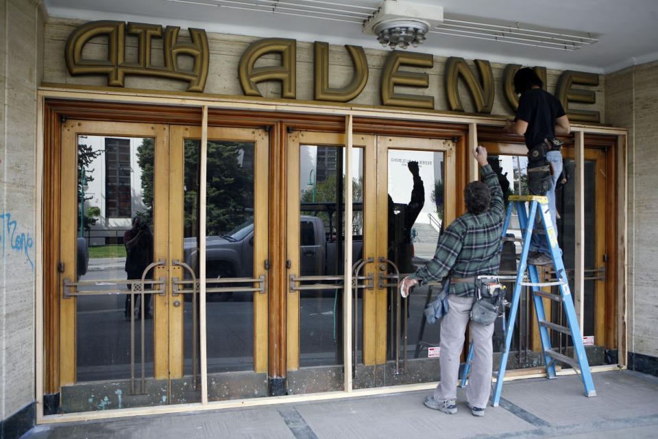 ** HOLD FOR STORY ** FILE - Jeff Griffin, left, and RC Edwardsen board up the 4th Avenue Theatre in downtown Anchorage, Alaska, on May 22, 2009. Demolition will begin in August 2022 on a once-opulent downtown Anchorage movie theater designed by the architect of Hollywood's famed Pantages Theater. The 4th Avenue Theatre with nearly 1,000 seats opened in 1947, and it withstood the second most powerful earthquake ever recorded. (AP Photo/Al Grillo, File)