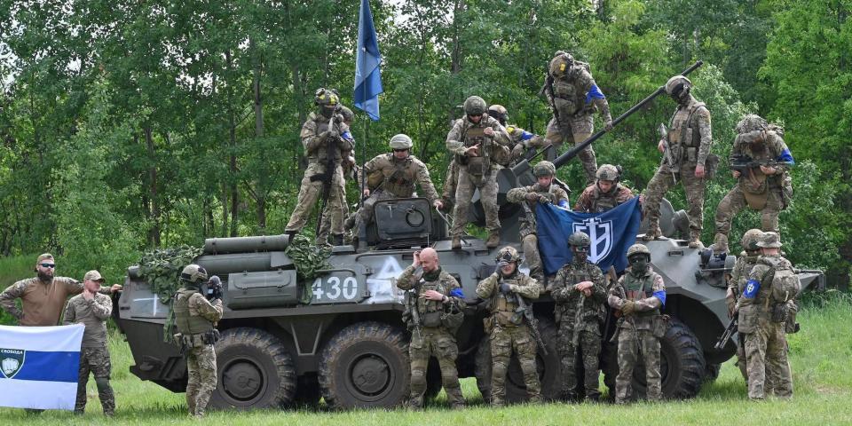 Fighters of the Russian Volunteer Corps and allied group, the Freedom of Russia Legion, pose with a seized armored personnel carrier from their May 2023 raid into southern Russia.