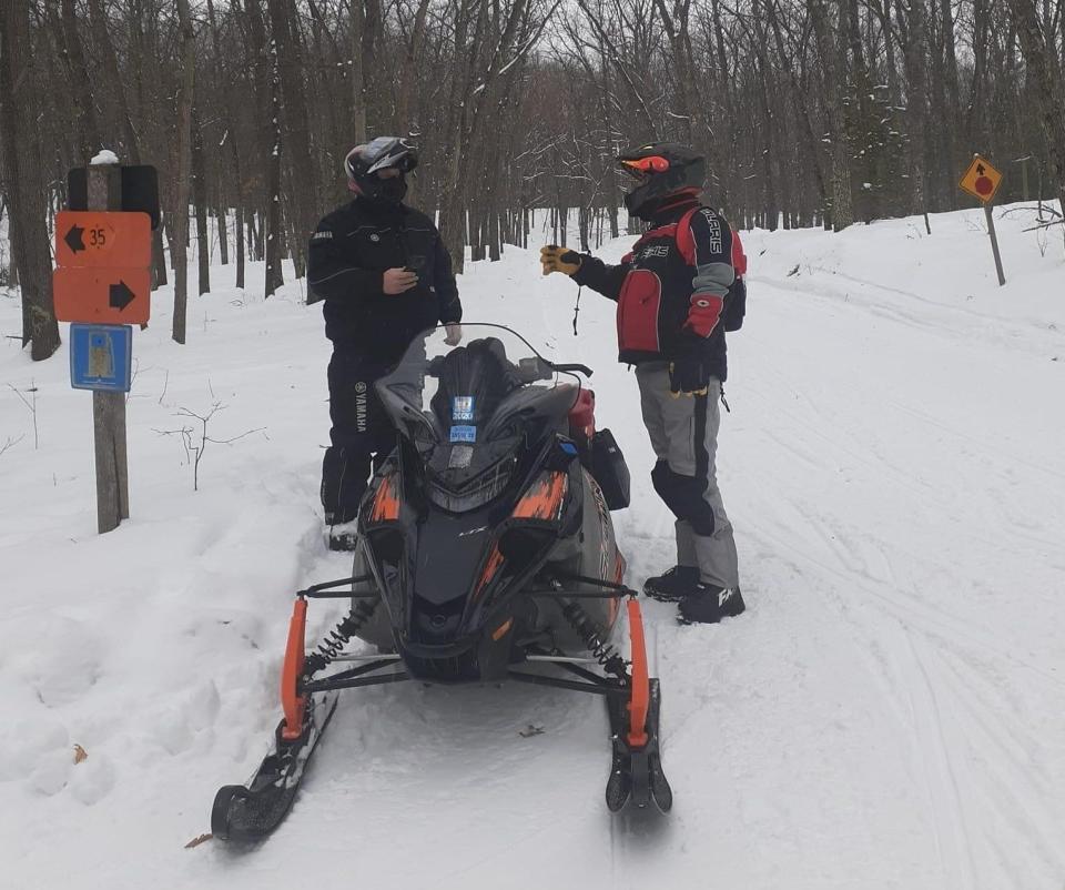 Snowmobilers stop near trail signs along Trail 35 in Lake County, Mich., which is maintained by the Trailriders Snowmobile Club in Baldwin.