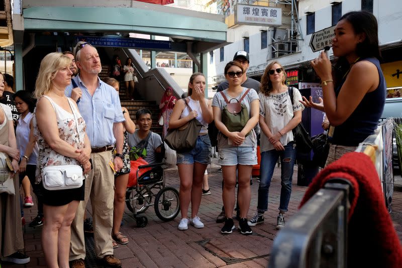 Tour guide Alla Lau speaks to tourists that join a free tour at Mong Kok district in Hong Kong