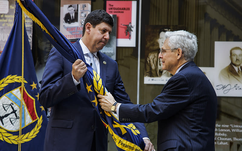 Attorney General Merrick Garland passes a flag to Steven Dettelbach