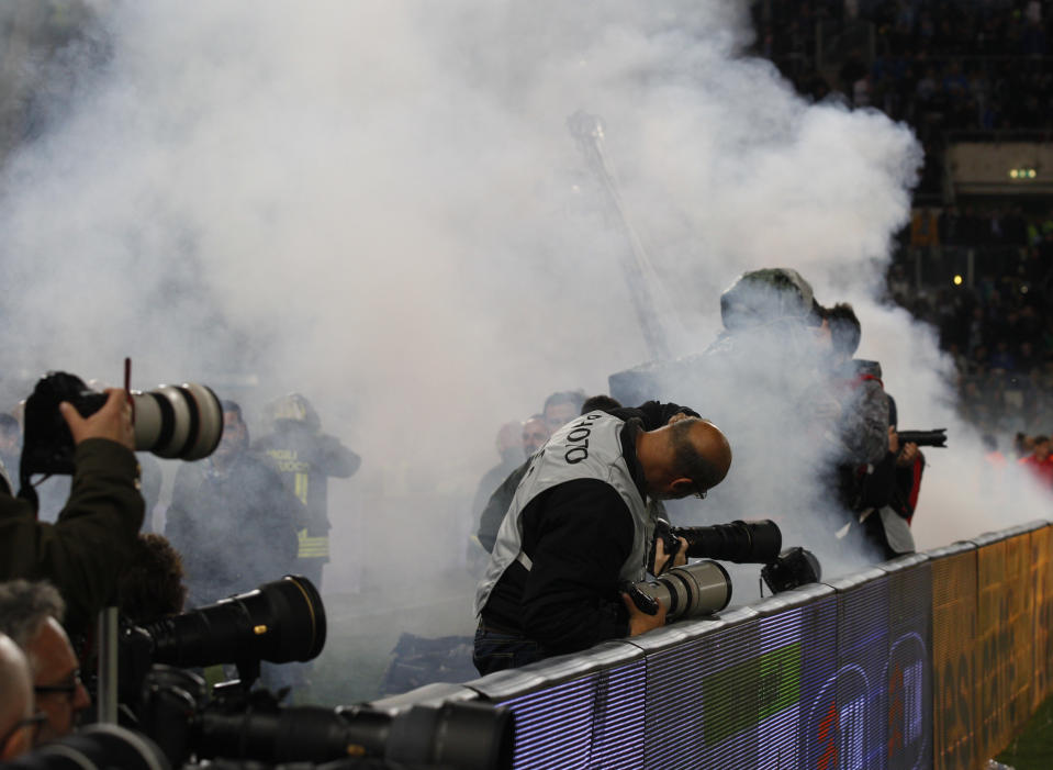 Photographers are covered by smoke from flares and fireworks thrown by supporters during the Italian Cup final soccer match between Fiorentina and Napoli Rome's Olympic stadium, Saturday, May 3, 2014. (AP Photo/Alessandra Tarantino)
