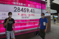 People wearing face masks walk past a bank's electronic board showing the Hong Kong share index in Hong Kong, Tuesday, June 22, 2021. Asian shares have rebounded from their retreat a day earlier, tracking Wall Street's recovery from the Federal Reserve's reminder it will eventually provide less support to markets. (AP Photo/Kin Cheung)
