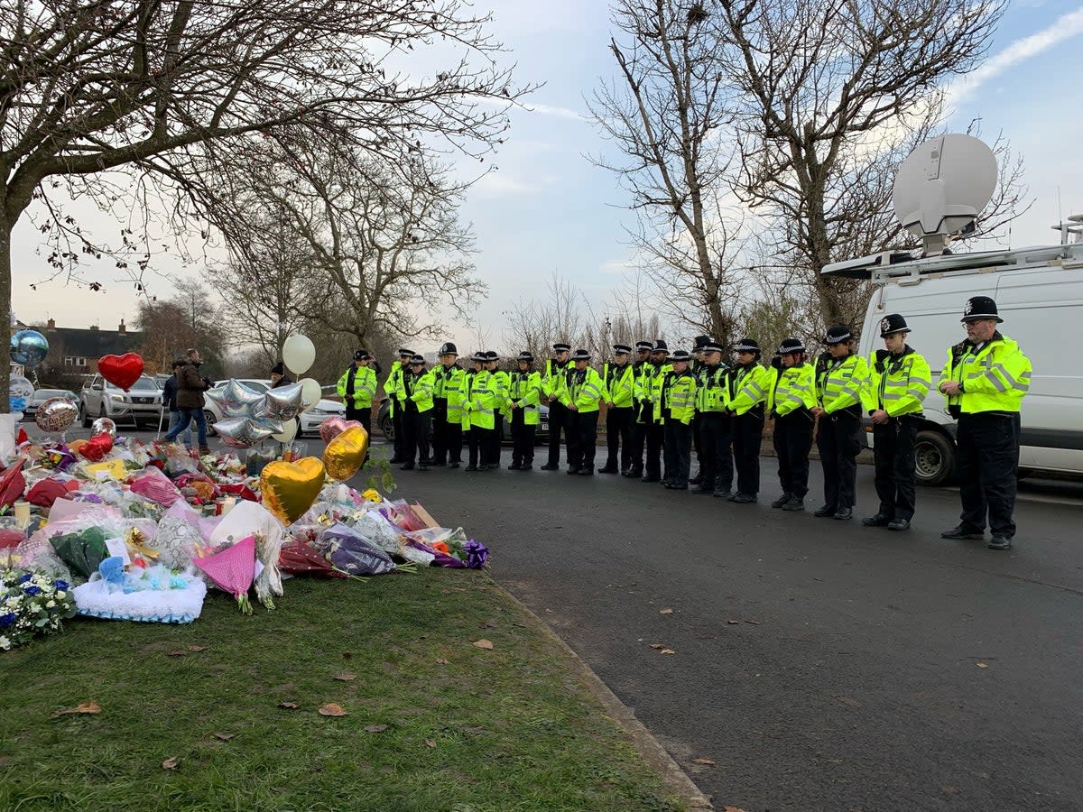 Officers from West Midlands Police lay bouquets of flowers and stood in silence near to the scene in Babbs Mill Park in Kingshurst, Solihull (PA)