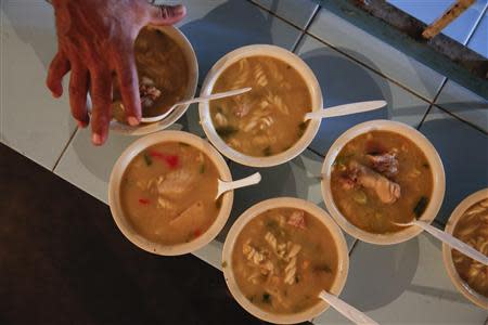 A man picks up a bowl of soup at the Mother Teresa of Calcutta eating center in Caracas March 17, 2014. REUTERS/Carlos Garcia Rawlins