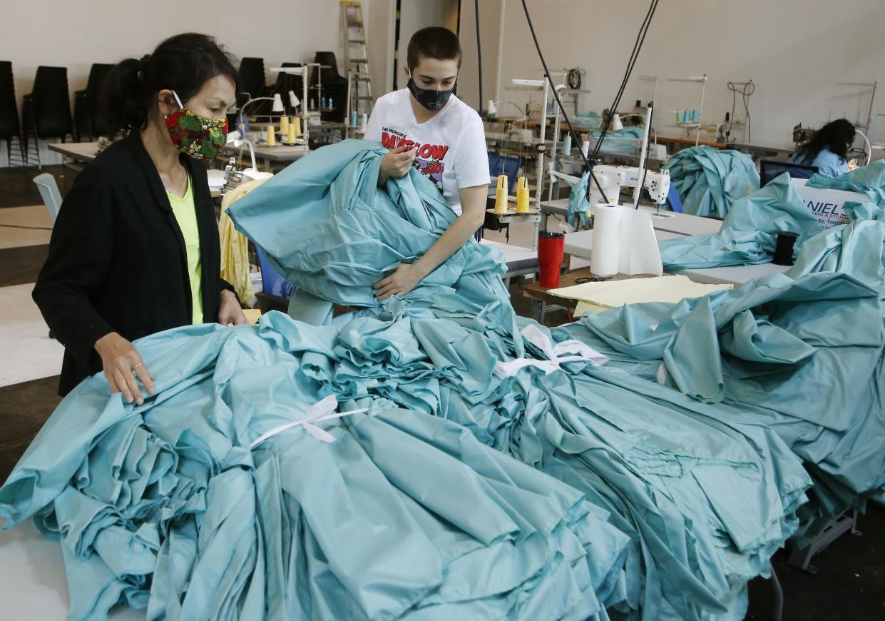 Workers at F.A.B.R.I.C., a non-profit organization providing resources for emerging fashion designers, looks through newly made PPE for area Dignity Health employees due to the coronavirus on Monday, April 13, 2020, in Tempe, Ariz. F.A.B.R.I.C. is working around the clock to create thousands of FDA-approved isolation gowns for local workers on the front lines of the pandemic.