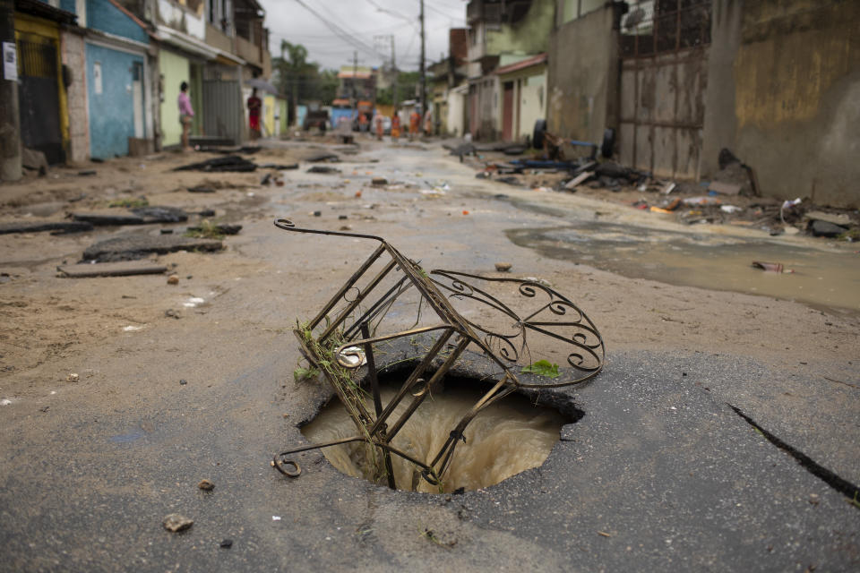 The metal frame of a chair of a is lodged at the mouth of a damaged manhole after heavy rains caused flashfloods in the Realengo neighborhood of Rio de Janeiro, Brazil, Monday, March 2, 2020. The water flooded the streets and entered homes of residents, with at least 4 deaths reported. (AP Photo/Silvia Izquierdo)