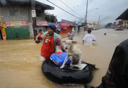 A resident pushes an improvised inflatable boat loaded with his dog through flood waters as they head for a safer area in the village of Tumana, Marikina town, in suburban Manila, after torrential rains inundated most of the capital