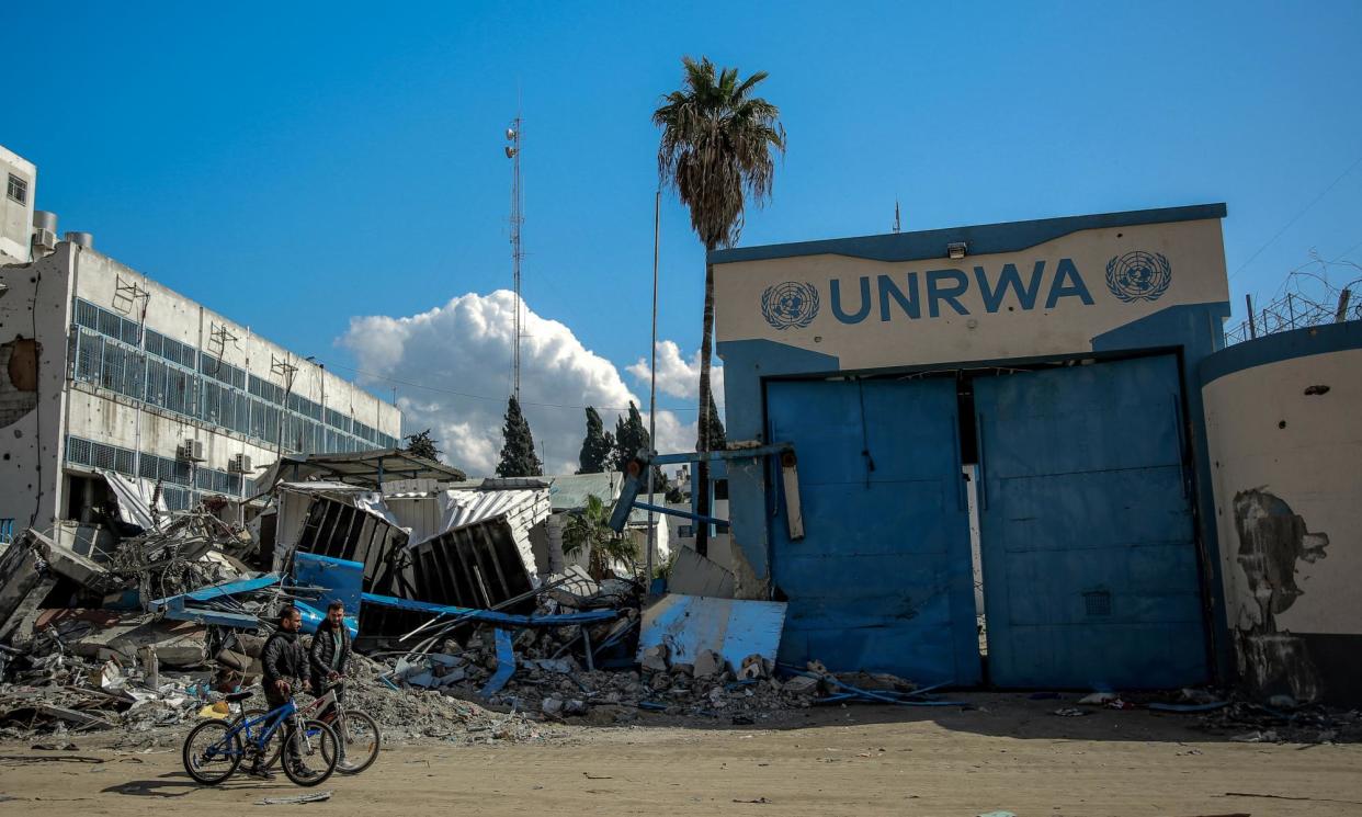 <span>People walk past the damaged Gaza City headquarters of the United Nations Relief and Works Agency for Palestine Refugees (UNRWA) on February 15, 2024</span><span>Photograph: AFP/Getty Images</span>