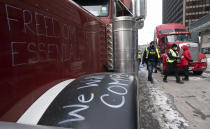 Police distribute notices to protesters in the downtown, Wednesday, Feb. 16, 2022 in Ottawa. Ottawa’s police chief was ousted Tuesday amid criticism of his inaction against the trucker protests that have paralyzed Canada's capital for over two weeks, while the number of blockades maintained by demonstrators at the U.S. border dropped to just one. (Adrian Wyld /The Canadian Press via AP)