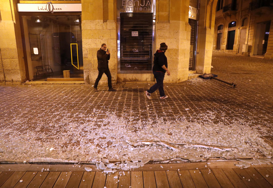 Lebanese men pass in front of a coffee shop that was smashed by anti-government protesters, during a protest against the new government, in downtown Beirut, Lebanon, Wednesday, Jan. 22, 2020. Lebanon's new government, made up of members nominated by the Shiite group Hezbollah and its allies got down to business Wednesday, a day after it was formed. Questions arose immediately about its ability to halt a spiral of economic and political collapse. (AP Photo/Hussein Malla)