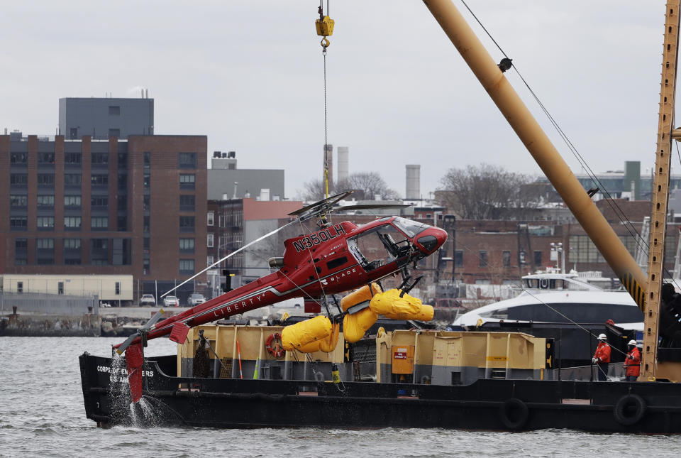 FILE - In this March 12, 2018 file photo, a helicopter is hoisted by crane from the East River onto a barge in New York. Federal investigators said Tuesday, Dec. 10, 2019, the helicopter company, whose doors-off flight crashed in a New York City river last year, exploited a regulatory loophole to avoid stricter safety requirements. (AP Photo/Mark Lennihan, File)