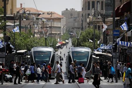 Pedestrians cross a street next to the light rail trams in Jerusalem May 11, 2017. Picture taken May 11, 2017. REUTERS/Amir Cohen