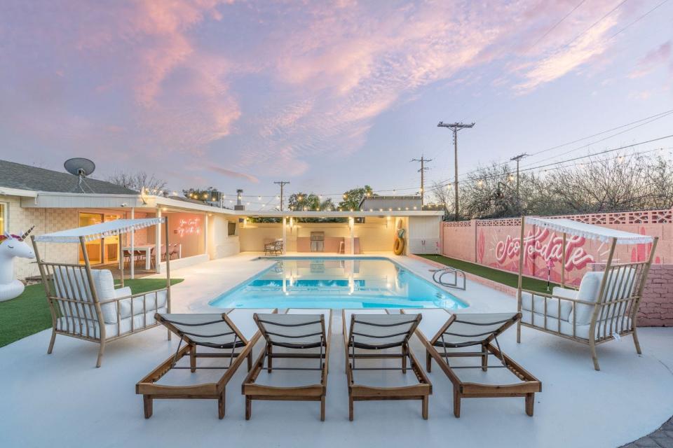 A pool surrounded by big chairs.