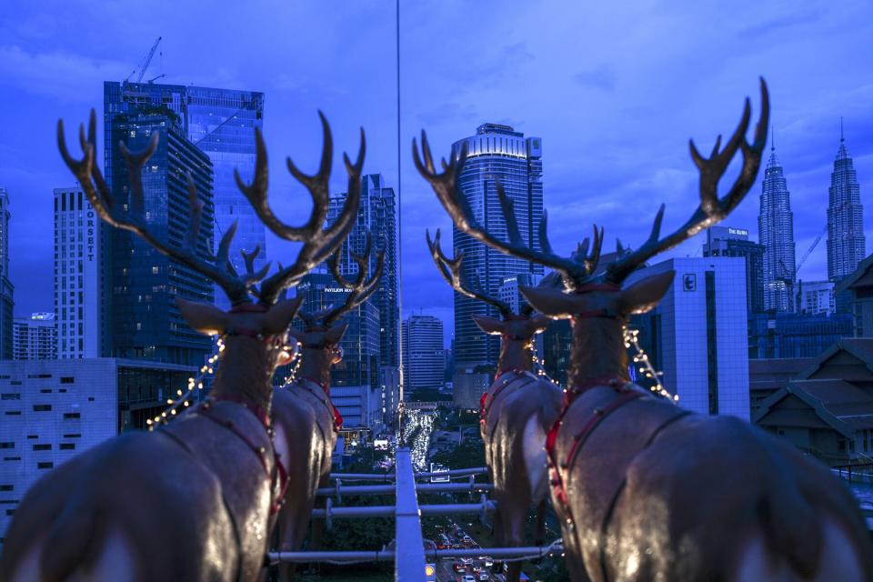 Pertonas Twin Towers at right seen from a hanging restaurant suspended by a crane overlooking the skyline of Kuala Lumpur inspired by Santa Claus travelling on a sleigh with reindeers for a Christmas season promotion.