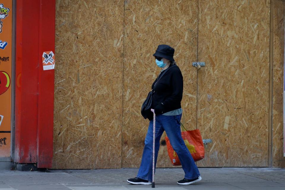 A shopper passes a boarded up shop on Oxford Street: AP