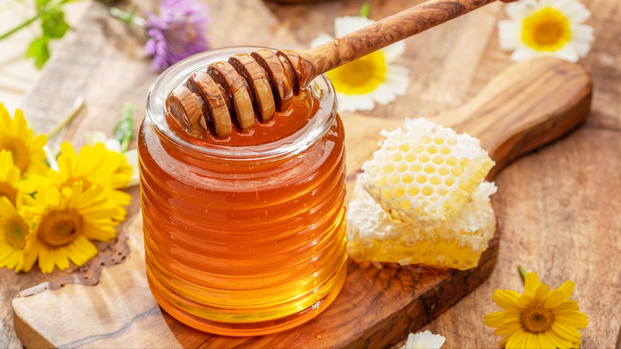  Honey in a jar on a wooden plate. 