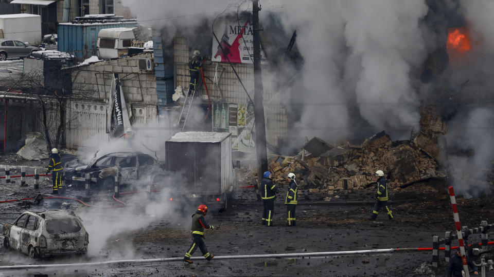 Fire and rescue workers attend to a building hit by a missile in central Kyiv on Wednesday