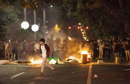 Demonstrators set fire to trash cans, as they protest against a chemical plant project, on a street in Maoming, Guangdong province, early April 1, 2014. REUTERS/Stringer