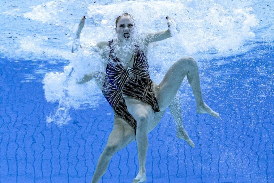 Two swimmers seen underwater, with one with a very intense facial expression