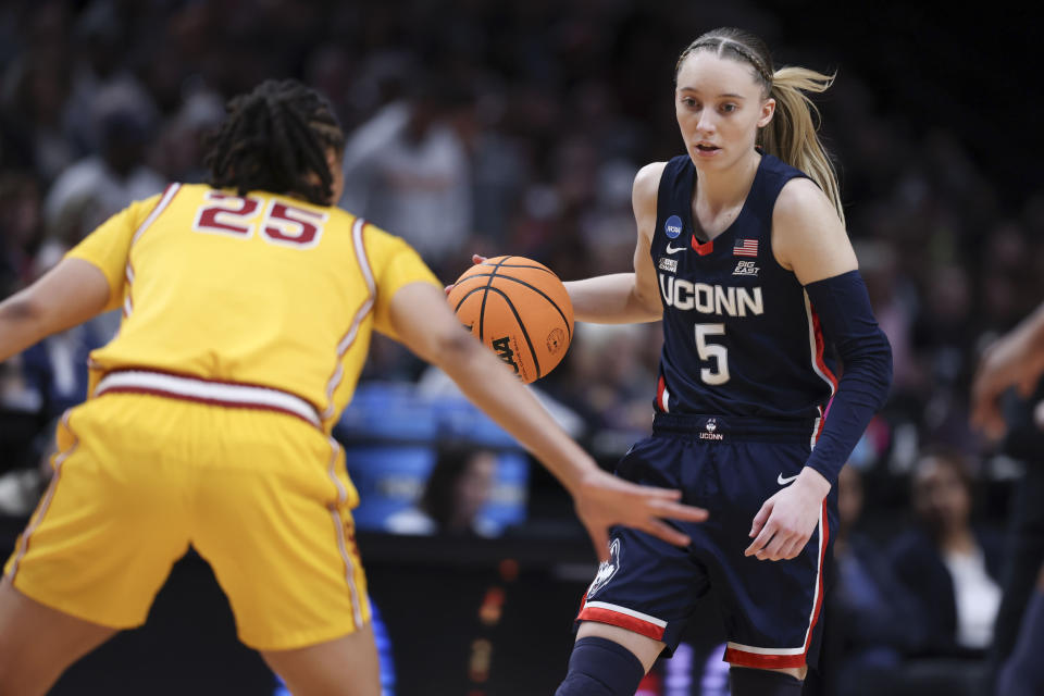 FILE - UConn guard Paige Bueckers (5) dribbles as Southern California guard McKenzie Forbes (25) defends during the first half of an Elite Eight college basketball game in the women's NCAA Tournament, April 1, 2024, in Portland, Ore. Southern California and UConn have agreed to a home-and-home series, which will have stars JuJu Watkins and Bueckers facing off against each other in December. (AP Photo/Howard Lao, File)