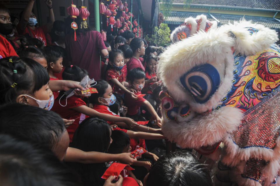 Students put red envelopes containing money, known locally as "ang pao," into the mouth of the "barongsai," or lion dance, during Lunar New Year celebrations at a school in Solo, Central Java, Indonesia, Jan. 19, 2023.<span class="copyright">Agoes Rudianto—Anadolu Agency/Getty Images</span>