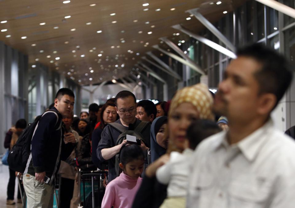 Passengers queue for a security screening before boarding the Malaysia Airlines Boeing 777-200ER flight MH318 to Beijing at Kuala Lumpur International Airport