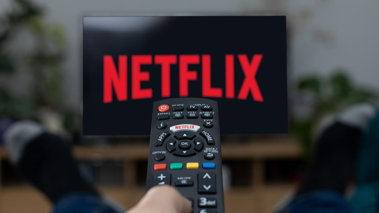  Netflix logo on a TV screen with a remote pointing at it. 