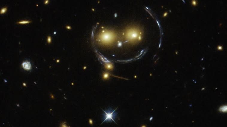  A telescope image of warped yellow starlight forming a smily face against a black background 