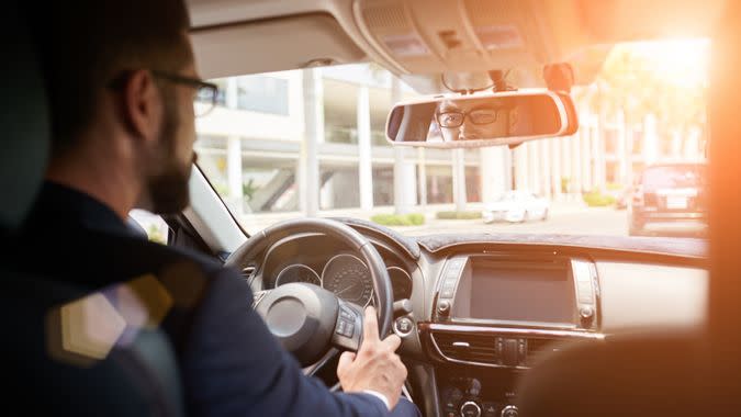 Young businessman driving to work, view over the shoulder.