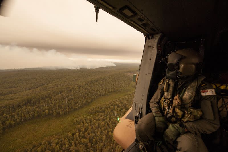 A Royal Australian Navy MRH-90 helicopter crew member, observes the fires on approach to Cann River in Gippsland