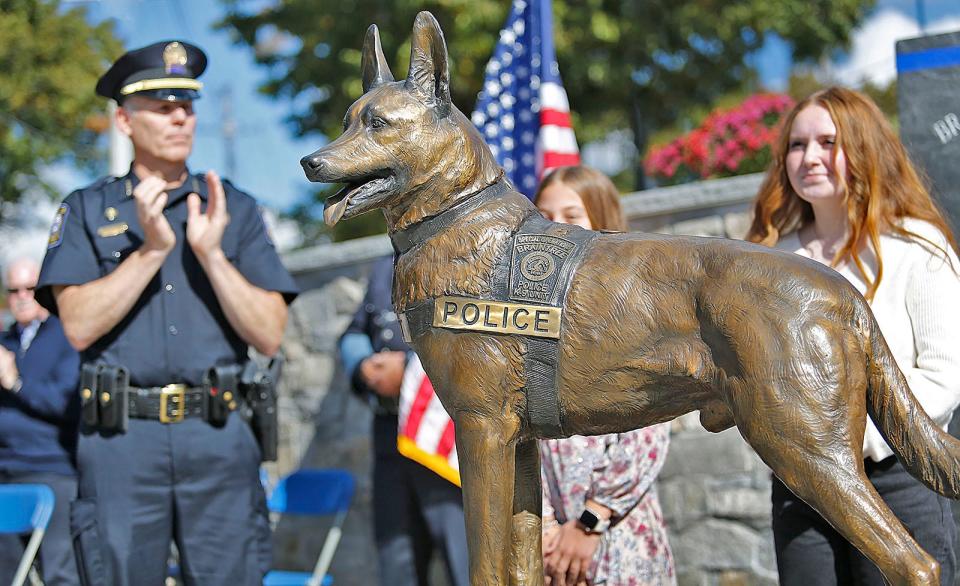 Former Braintree Police Chief Mark Dubois, now chief in Portland, Maine, applauds the Kitt statue during a Braintree police ceremony to dedicate a statue of fallen K-9 officer Kitt and to rededicate the police memorial at the station on Thursday, Oct. 19, 2023.
