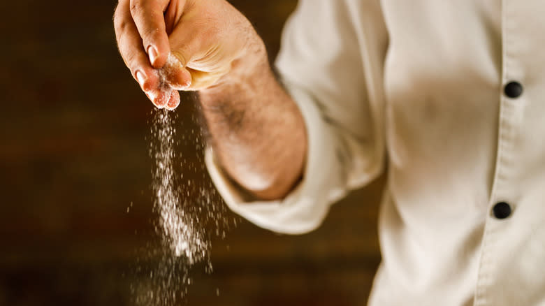 A chef sprinkles salt