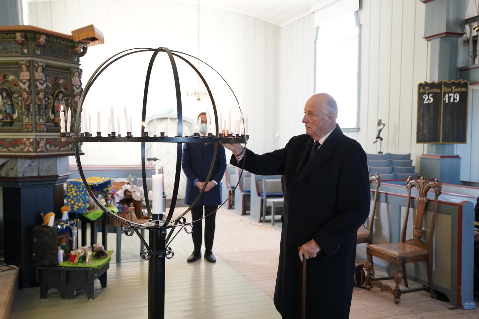 King Harald of Norway light candles in Gjerdrum church to remember the victims after the landslide in Ask, Norway, Sunday, Jan. 3, 2021. Rescue teams searching for survivors four days after a landslide carried away homes in a Norwegian village have found no signs of life amid the ruined buildings and debris. (Lise Aaserud/NTB via AP)