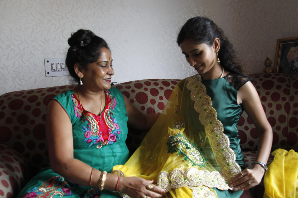 In this Aug 1, 2013 photo, Shagun TV participant Nidhi Gaur, right, shows her mother a traditional Indian dress that she intends to wear at her wedding in New Delhi, India. Indians are obsessed with weddings and obsessed with reality television. Now Shagun TV, a new television channel headquartered in a sprawling suburb of India's capital, is hoping it has found a can't-miss idea — merging the two into a 24-hour matrimonial TV station.(AP Photo/ Shivan Sarna )