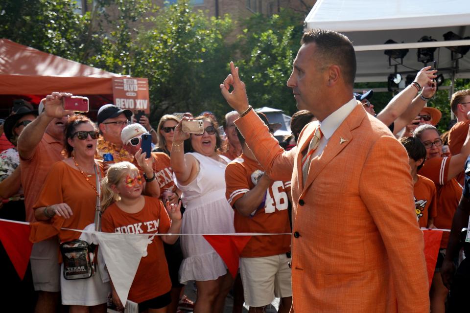 Texas head coach Steve Sarkisian flashes a Hook 'em sign to fans as he walks down Bevo Blvd ahead of the Sept. 17 win over UTSA. On Saturday night, after the loss to Oklahoma State, he and several players skipped the on-field singing of "The Eyes of Texas." On Monday, he apologized.