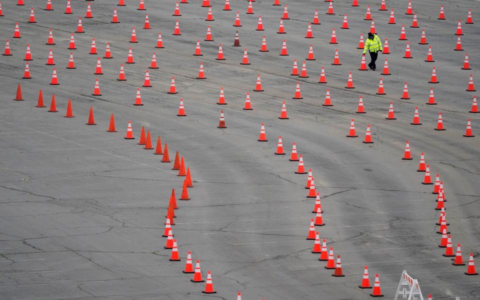 A worker arranges cones at a mostly-empty vaccination site at Dodger Stadium. A nationwide shortage of jabs is hindering efforts to vaccinate residents of California and other states. LA temporarily shut down five mass vaccination sites after running out of vaccine. - AP Photo/Marcio Jose Sanchez