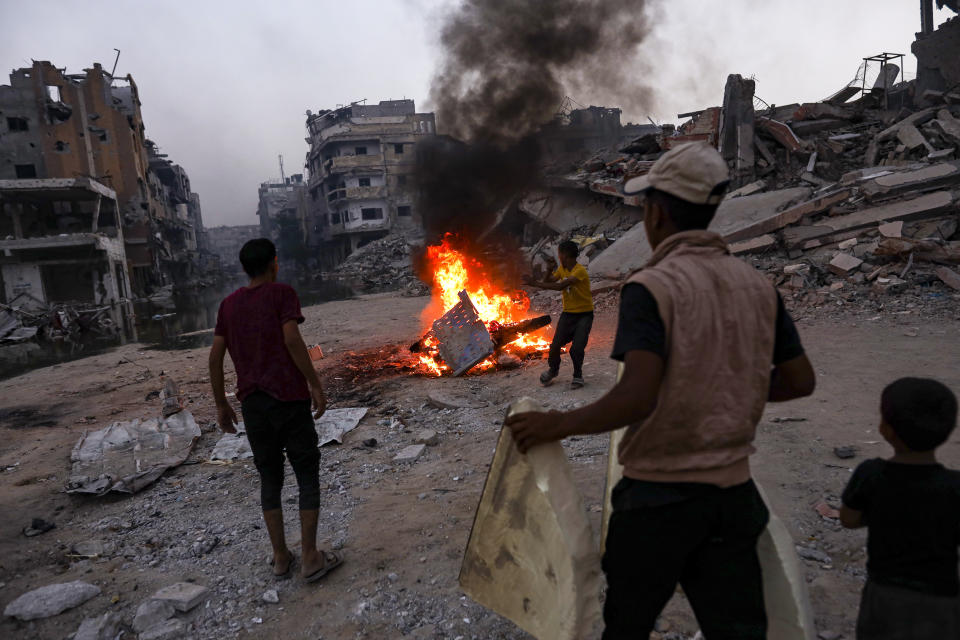 Palestinians displaced by the Israeli air and ground offensive on the Gaza Strip, light a fire to keep away mosquitoes and other insects, which have recently infested the streets of the southern town of Khan Younis, Gaza Strip, Thursday, July 4, 2024. (AP Photo/Jehad Alshrafi)