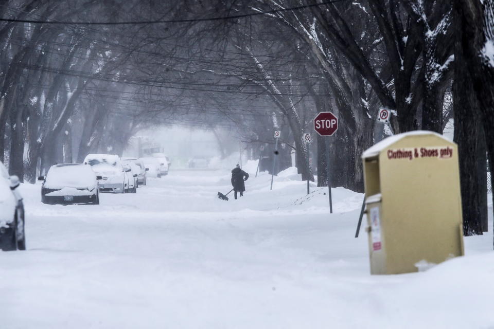 A woman shovels snow from an empty street as a snowstorm enters its second day in Winnipeg, Manitoba, Canada April 14, 2022. REUTERS/Shannon VanRaes