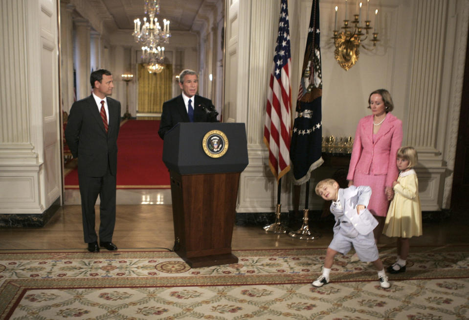 FILE - President Bush introduces his nominee for the Supreme Court, John G. Roberts Jr., left, as his son John, age 4, dances, and wife Jane and daughter Josephine, age 5, look on in the State Dining Room at the White House, July 19, 2005, in Washington. When political kids upstage their parents, it brings a moment of levity to the official workings of government. It’s also a solid case study on the sheer unifying power of humor. (AP Photo/Charles Dharapak, File)