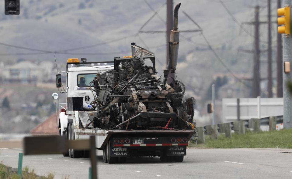 What remains of a semi-tractor and trailer are carried away as workers clear debris from the eastbound lanes of Interstate 70 on Friday, April 26, 2019, in Lakewood, Colo., after a deadly pileup involving semi-truck hauling lumber on Thursday. Lakewood police spokesman John Romero described it as a chain reaction of crashes and explosions from ruptured gas tanks. "It was crash, crash, crash and explosion, explosion, explosion," he said. (AP Photo/David Zalubowski)