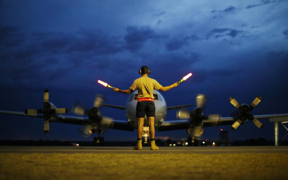 FILE - In this Monday, March 24, 2014, file photo, a ground controller guides a Royal Australian Air Force AP-3C Orion to rest after sunset upon its return from a search for the missing Malaysia Airlines Flight 370, over the Indian Ocean, at the Royal Australian Air Force Base Pearce in Perth, Australia. The disappearance of Malaysia Airlines Flight 370 has presented two tales of modern technology. The public has been surprised to learn of the limitations of tracking and communications devices, which contributed to the plane vanishing for more than two weeks. But the advanced capabilities of some technologies, particularly satellites, have provided hope that the mystery won't go unsolved. (AP Photo/Jason Reed, Pool, File)