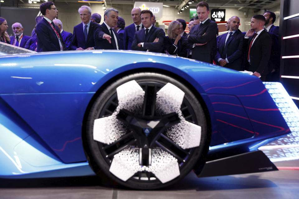 Renault's Chief Executive Luca De Meo, center left, gestures as he speaks with French President Emmanuel Macron, center right, at the Paris Car Show, Monday, Oct. 17, 2022. Europe is leading the charge into electric vehicles as battery powered cars break out of their niche market of first adopters and enter the mainstream with increasing market share that's forecast to grow strongly as the EU pushes to phase out internal combustion engine vehicles by 2035 (Gonzalo Fuentes/Pool via AP)