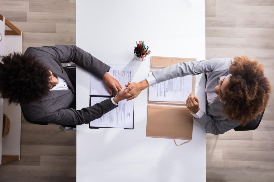 An overhead shot of a business manager and job applicant shaking hands.